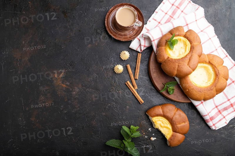 Sour cream bun with cup of coffee on a black concrete background and linen textile. top view, flat lay, copy space