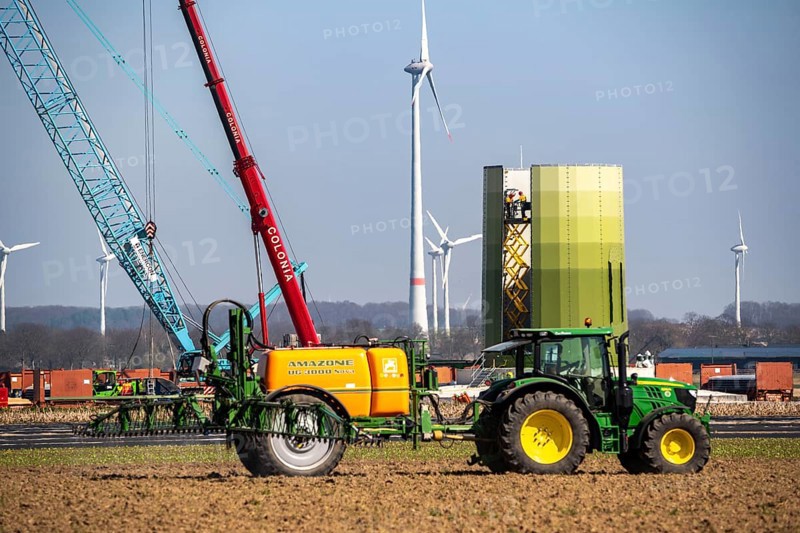 Construction of a wind turbine, Enercon steel pillar, near Kerken, Kleve district, on the Lower Rhine, farmer applying pesticide, North Rhine-Westphalia, Germany, Europe