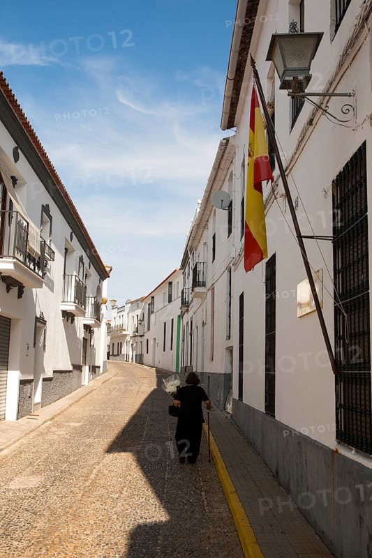 Woman walking along a quiet street in village of Jabugo, Sierra de Aracena, Huelva province, Spain, Europe