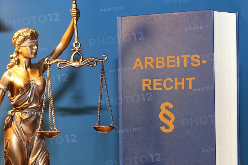 Symbolic image: Labour law reference book and a Justitia