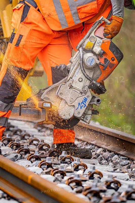 A construction worker uses a chainsaw to cut a track while sparks fly, track construction, Hermann Hessebahn, Calw, Black Forest, Germany, Europe