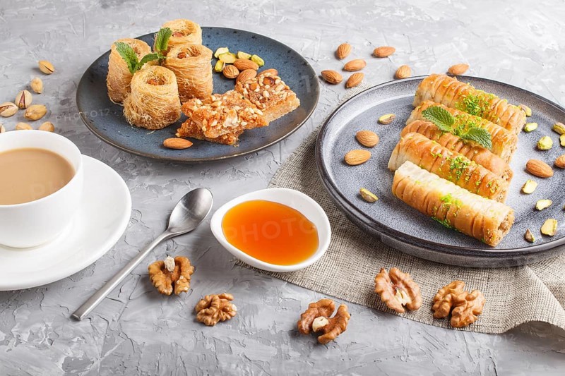 Set of various traditional arabic sweets: baklava, kunafa, basbus in ceramic plates on a gray concrete background. top view, flat lay