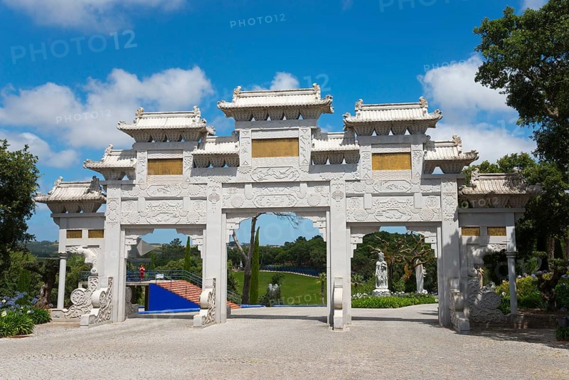 A traditional Chinese Tor in a sunny park with flowering shrubs and a bright blue sky, Bacalhôa, Bacalhoa Buddha Eden, Quinta dos Loridos, Europe's largest oriental garden, Bombarral, Oeste, Centro, Portugal, Europe