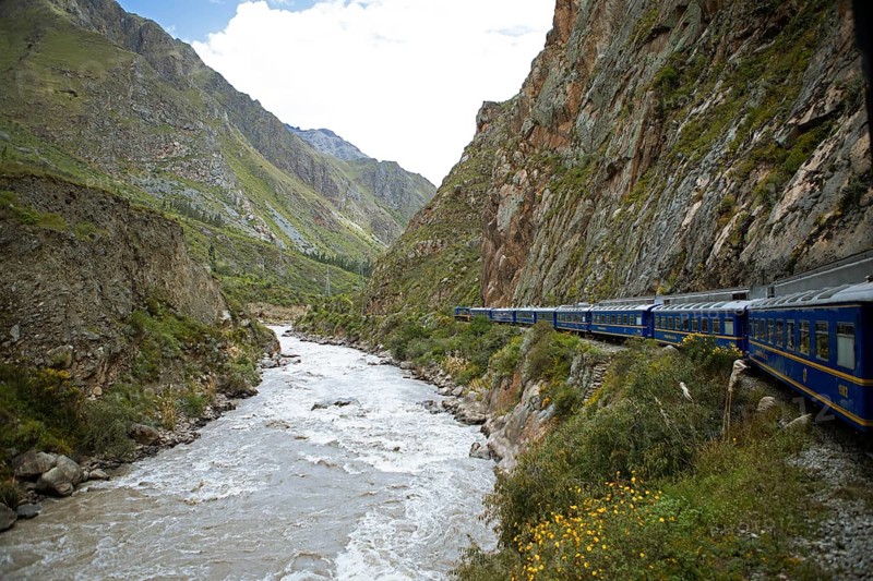 Perurail train travelling through the Andes from Ollantaytambo to Machu Picchu, in front the river Rio Urubamba, Cusco region, Peru, South America