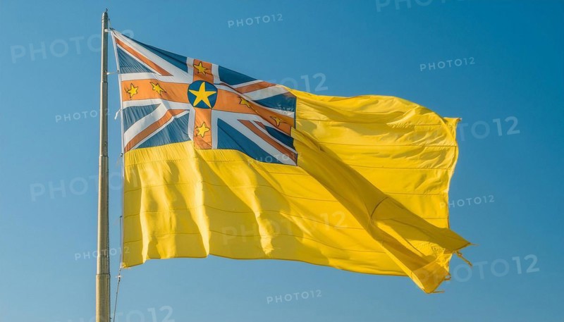 The flag of Niue, an island state in the Pacific Ocean, flutters in the wind, isolated against a blue sky