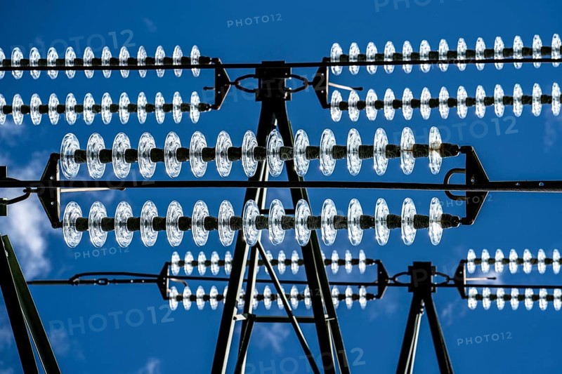 Insulators made of glass on a high-voltage line, they hang on the pylons as a suspension device between the pylon and the live, non-insulated cable, extra-high voltage line, symbolic image energy