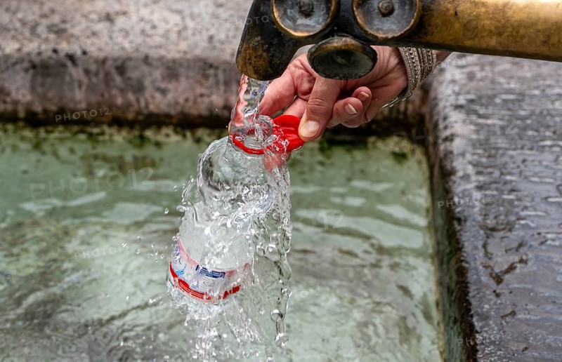 Water fountain, a woman fills drinking water into a small plastic bottle, Munich, Bavaria, Germany, Europe