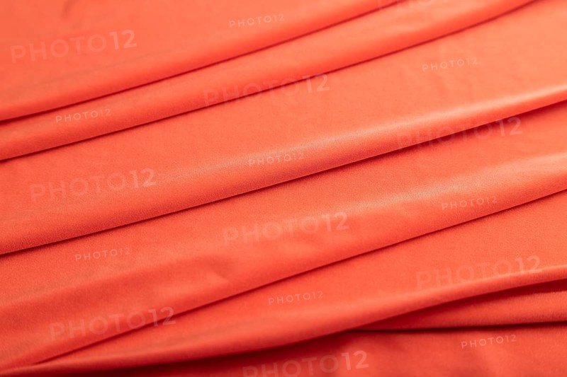 Fragment of red silk tissue. Side view, natural textile background and texture. wave concept, abstract