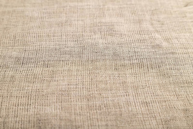 Fragment of smooth brown linen tissue. Side view, natural textile background and texture