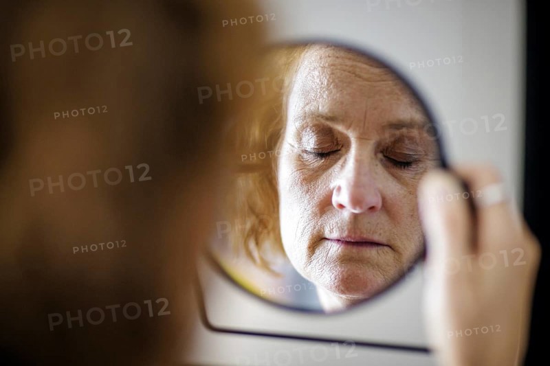 Symbol photo. An elderly woman with closed eyes can be seen in a mirror. Berlin, 13.08.2024