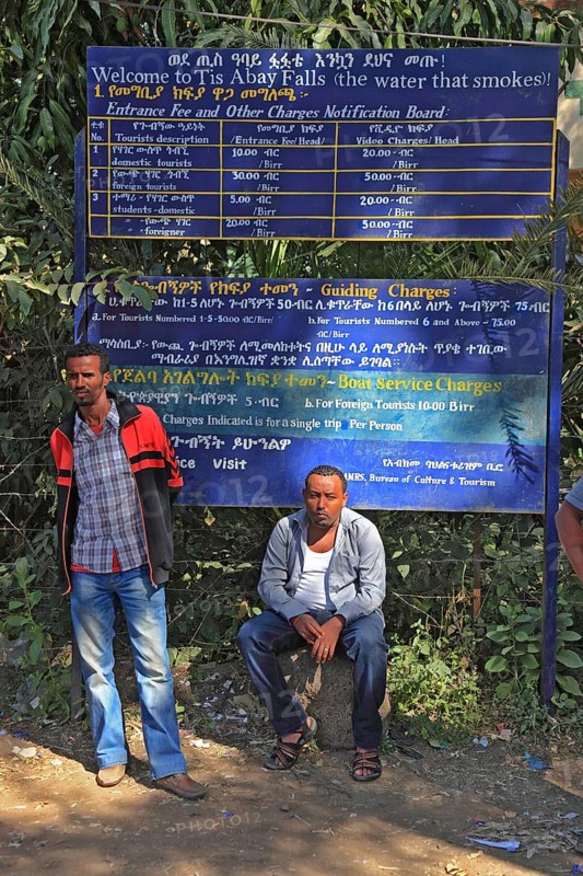Two locals in front of the price board with the fares for the trip to Abay Falls, Ethiopia, Africa