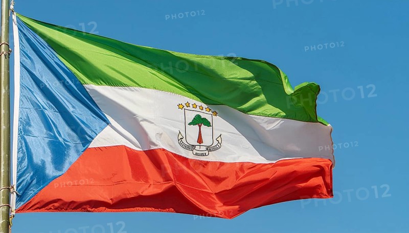 The flag of Equatorial Guinea flutters in the wind, isolated against a blue sky