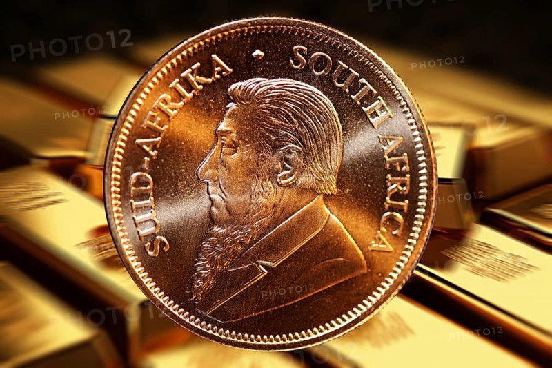 Close-up of a Krugerrand gold coin, in the background blurred gold bars (composing)