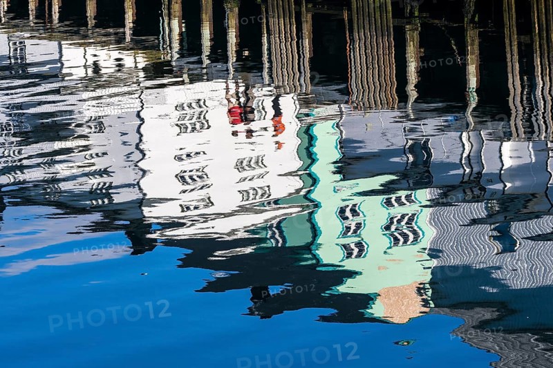 Pier at harbor in Henningsvær, reflections of wooden houses in the calm water, Austvagøy, Lofoten, Norway, Europe