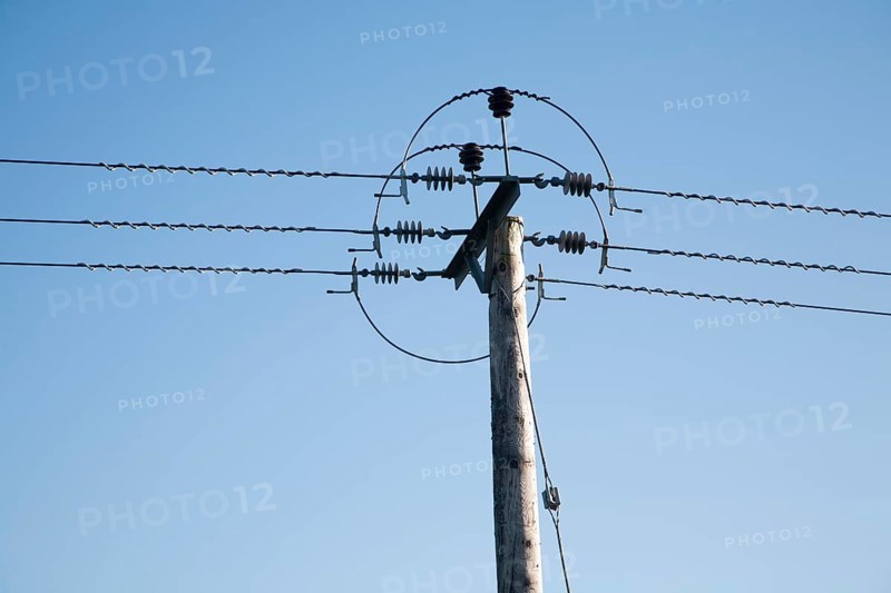 Close up of electricity cables and telegraph pole against blue sky, UK