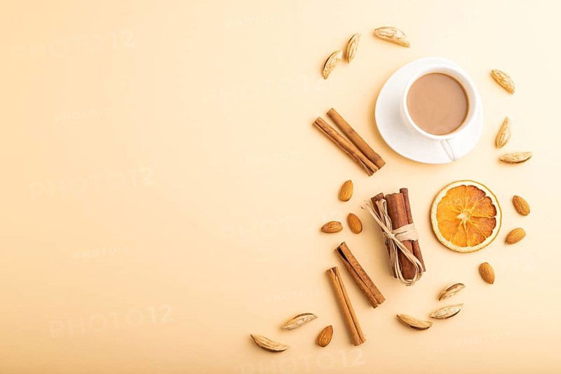 Composition with almonds, cinnamon and cup of coffee on orange pastel background. Blank, flat lay, top view, still life, copy space
