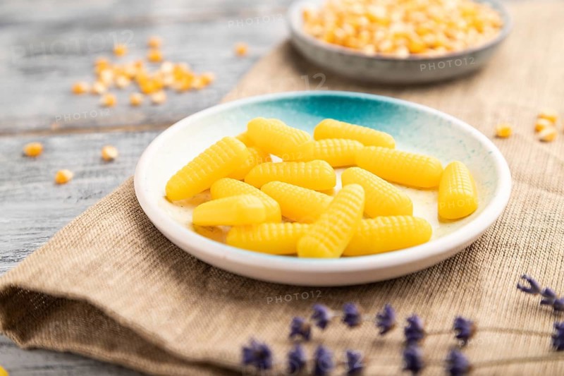 Jelly corn candies on gray wooden background and linen textile. close up, side view, selective focus