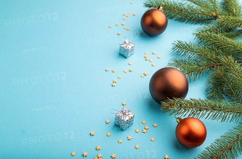 Christmas or New Year composition. Decorations, bronze balls, fir and spruce branches, on a blue paper background. Side view, copy space