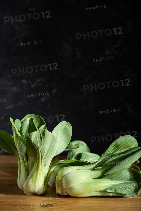 Fresh green bok choy or pac choi chinese cabbage on a gray wooden background. Hard light, contrast, dark, moody. Side view, copy space, selective focus