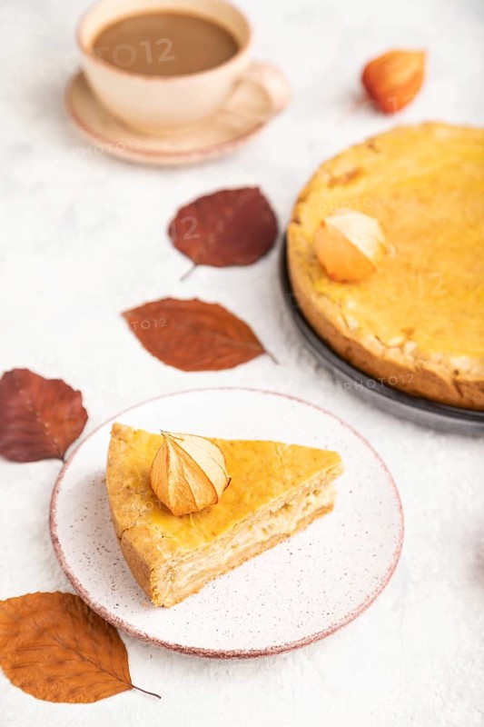 Autumn onion pie decorated with leaves and cup of coffee on gray concrete background. Side view, close up, selective focus