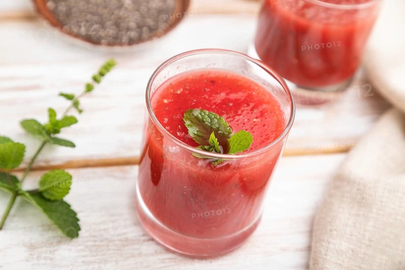 Watermelon juice with chia seeds and mint in glass on a white wooden background with linen textile. Healthy drink concept. Side view, close up, selective focus
