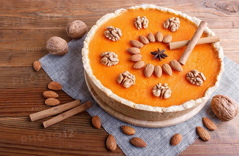 Traditional american sweet pumpkin pie decorated with nuts, on brown wooden background. close up, copy space