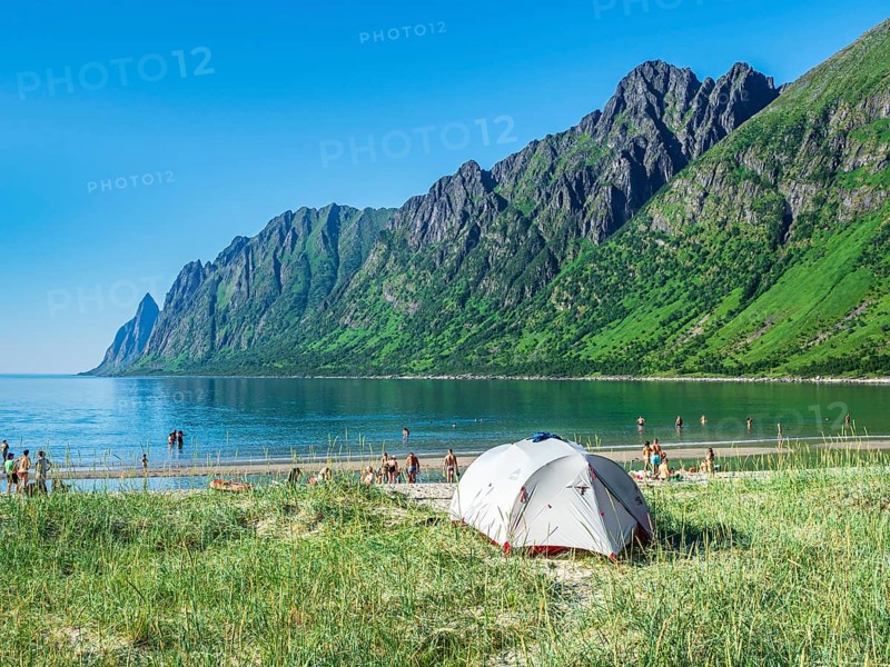 Beach Ersfjordstranden, fjord Ersfjord, public recreation area, tent on the beach, people enjoy the warm summer north the polar circle, view to mountain range Okshornan, island Senja, Troms, northern Norway, Norway, Europe