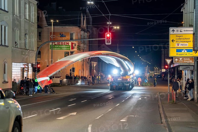 Transport of a 68 metre long, 22 tonne blade of a wind turbine, here in Schwelm, with a self-propelled Blade-Lifter vehicle, over a 40 km long route, over 2 nights, in the Bergisches Land, through towns, villages, over country roads, narrow through roads, to the construction site of the wind turbine near Hagen, North Rhine-Westphalia, Germany, Europe