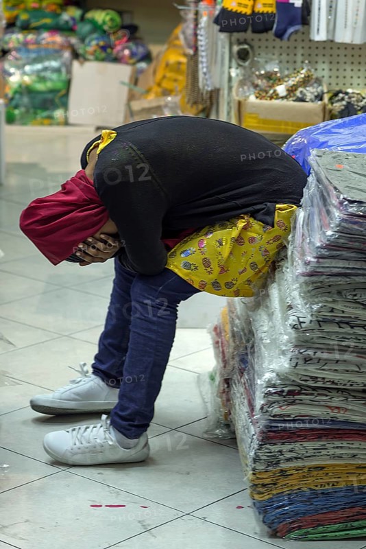 Tired sales assistant in a textile shop in the historic centre of Genoa, Italy, Europe