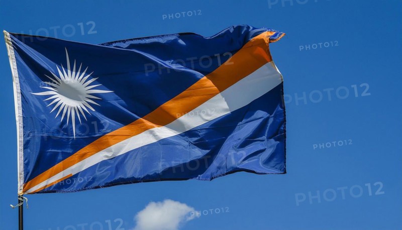 The flag of the Marshall Islands, Pacific Islands, flutters in the wind, isolated against a blue sky