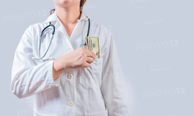 Unrecognizable doctor putting bribe money in pocket isolated. Dishonest female doctor putting money in pocket. Medical bribery concept