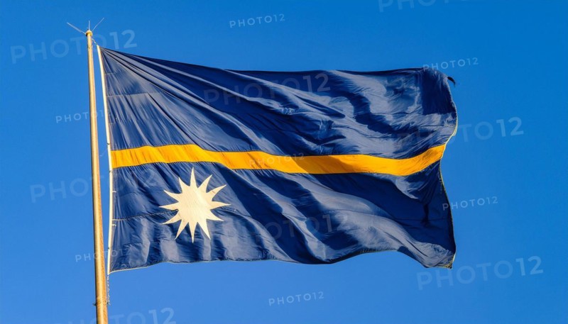 The flag of Nauru, an island nation in the Pacific Ocean, flutters in the wind, isolated against a blue sky