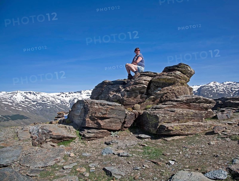 Woman sitting on rocky outcrop in the Sierra Nevada Mountains in the High Alpujarras, near Capileira, Granada Province, Spain, Europe