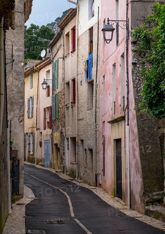 Narrow alley with old buildings and pastel-coloured walls, lanterns and Mediterranean charm in historic town, Vauvenargues, Provence-Alpes-Cote d'Azur, France, Europe