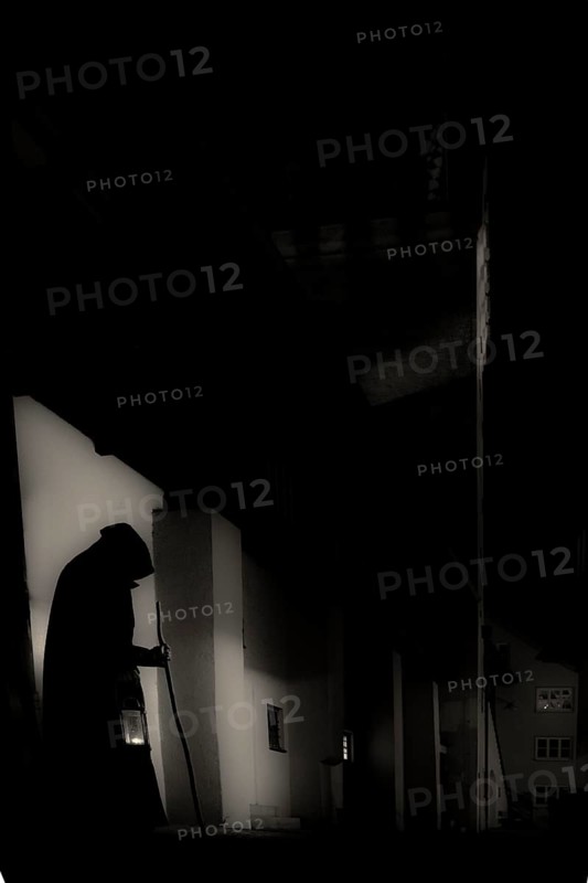 Old man with hood, stick and lantern in gloomy city neighbourhood, Mindelheim, Unterallgäu, Bavaria, Germany, Europe