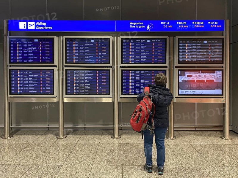 Elderly woman, best ager, standing in front of departure board, departure board, Terminal 2, Frankfurt am Main Airport, Hesse, Germany, Europe