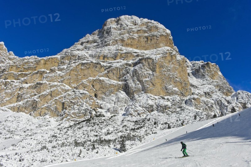Skiers on the descent from Col Pradat in front of the snow-covered peak of Sassongher, winter sports resort of Colfosco, Colfosco, Alta Badia ski area, Dolomites, South Tyrol, Italy, Europe