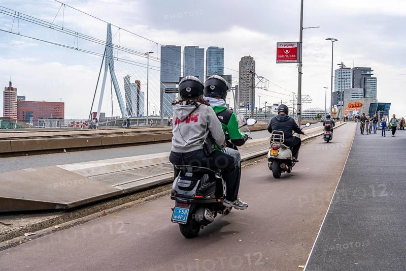Scooter, cyclist on the cycle path of the Erasmus Bridge over the Nieuwe Maas, skyline of skyscrapers on the Kop van Zuid, Rotterdam, Netherlands