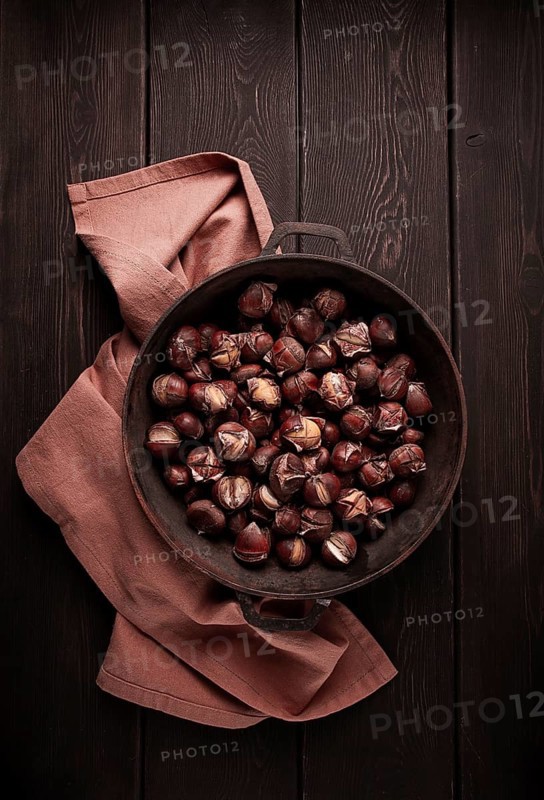 Roasted chestnuts, in an iron pan, wooden table, top view, no people, rustic style