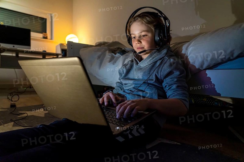 Boy, at home on the computer, laptop, in the children's room, playing a game, chatting with other children, fellow players