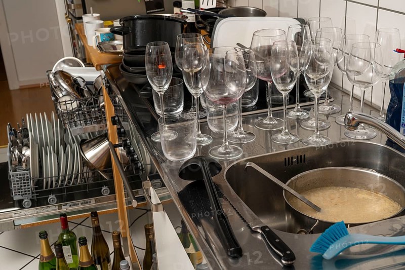 Kitchen after a big dinner, cooking party, dishwasher, full, with cleaned dishes, dirty glasses, pots, cooking utensils on the sink, waiting to be washed