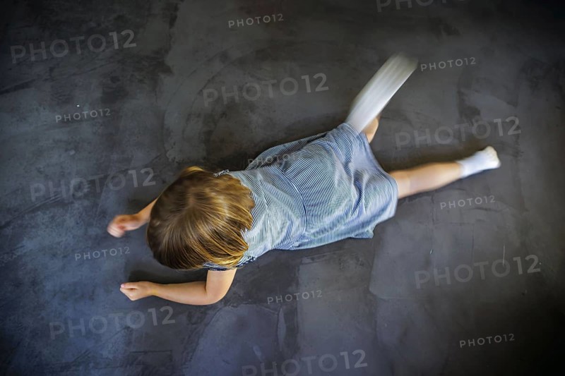 Symbol photo on the subject of tantrums (posed scene) . A little girl is lying on the floor, drumming her hands on the floor and is angry. Berlin, 21.08.2024