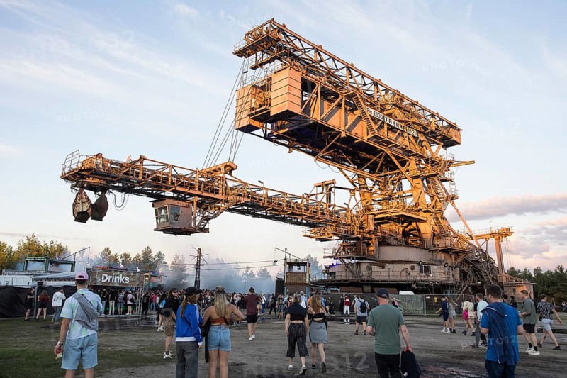 Festival visitors in front of an open-cast mining excavator illuminated by the evening sun at the Melt Festival in Ferropolis on 13 July 2024. After a total of 27 years, the festival will take place for the last time in 2024