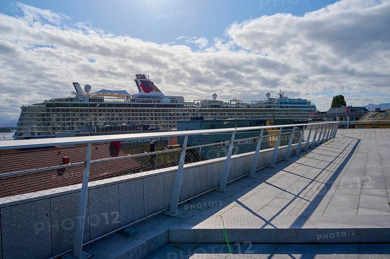 View from the event terrace More og Romsdal Art Centre to cruise ship, Mein Schiff 6, in the harbour on a sunny day with cloudy sky and architectural railing in the foreground, Molde, Romsdal, Norway, Europe