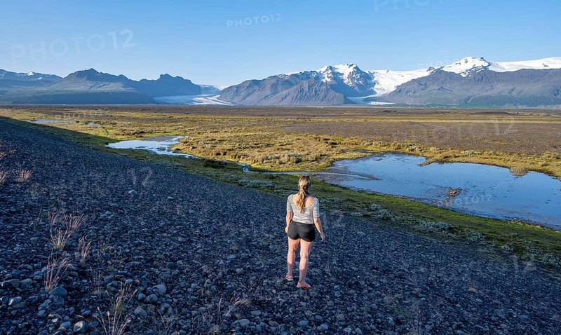 Tourist in front of Icelandic landscape, view of glacier tongues Skaftafellsjökull and Svínafellskökull, glaciated mountain peak Hrútfjallstindar and mountain Kristínartindar, Vatnajökull National Park, Austurland, Iceland, Europe