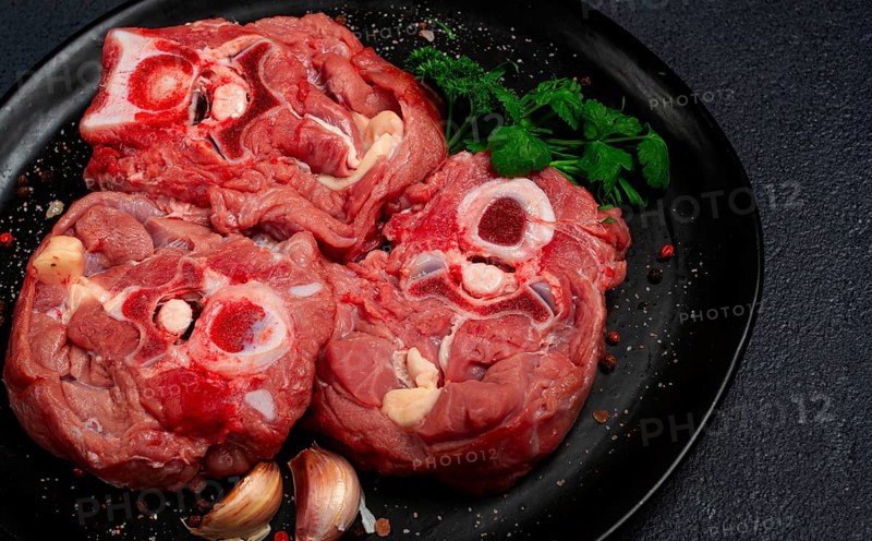 Raw steak, calf's neck on the bone, fresh meat, on a black plate, top view, no people