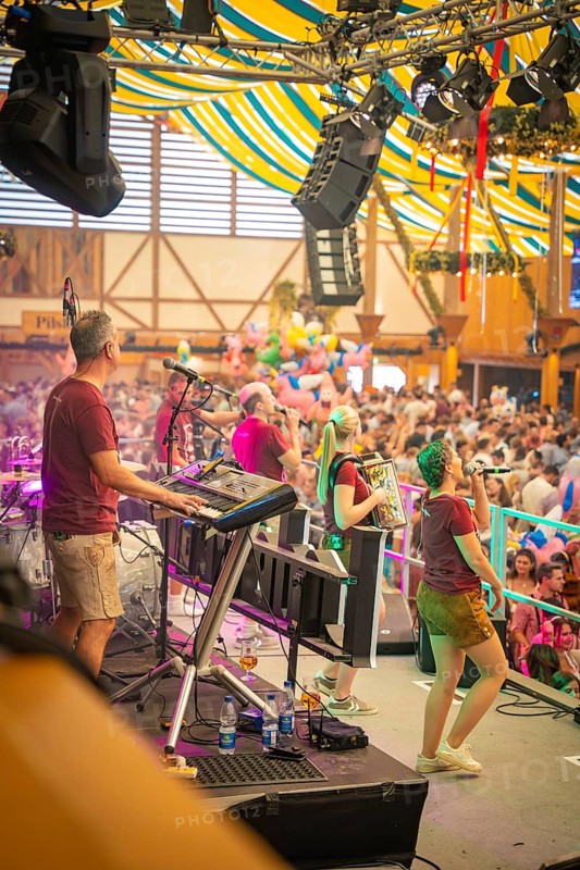 Band plays on a stage in a colourful marquee in front of a large crowd, Canstatter Wasen, Stuttgart, Germany, Europe