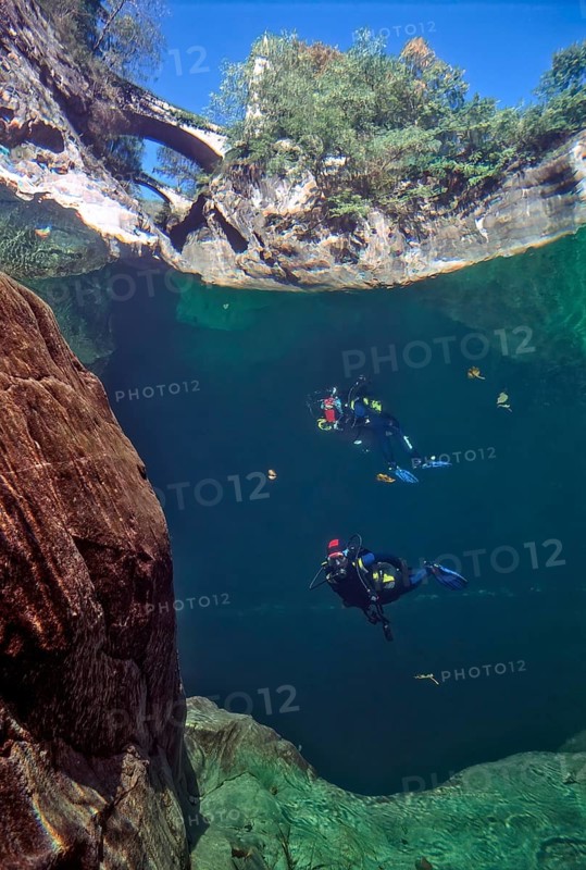 View from underwater through the water surface of the river Orrido di Sant' Anna on top foreground bridge from the Middle Ages behind it Roman bridge from Roman times, below reflection in the water con scuba diver diver with diving equipment reflected in underwater canyon, Traffiume, Cannobio, Verbania, Piedmont, Italy, Europe