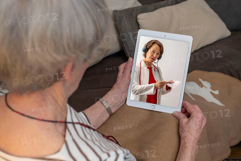 Symbolic image of telemedicine, patient speaking to a doctor in a video conference from home