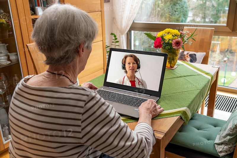 Symbolic image of telemedicine, patient speaking to a doctor in a video conference from home